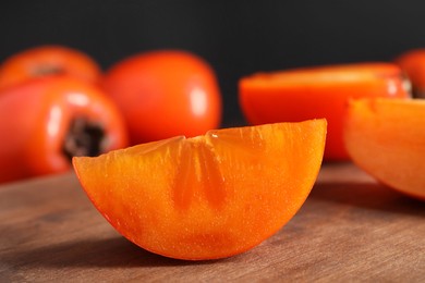 Piece of delicious ripe persimmon on wooden board, closeup