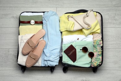 Open suitcase packed for trip on floor, top view