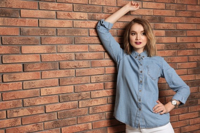 Photo of Beautiful young woman posing near brick wall