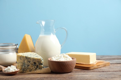 Photo of Different dairy products on wooden table against blue background