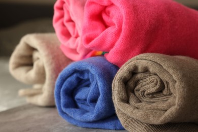 Photo of Rolled color sweaters on table, closeup view