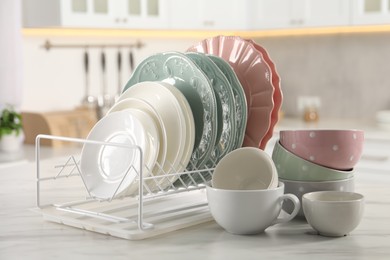 Many different clean dishware and cups on white marble table in kitchen