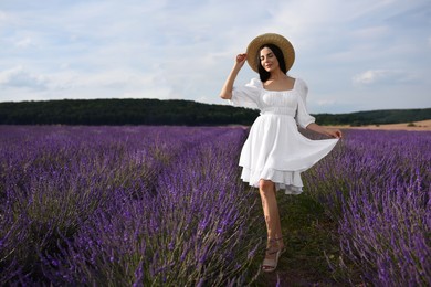 Beautiful young woman walking in lavender field