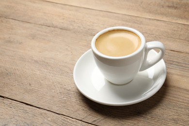 Photo of Aromatic coffee in cup on wooden table. Space for text