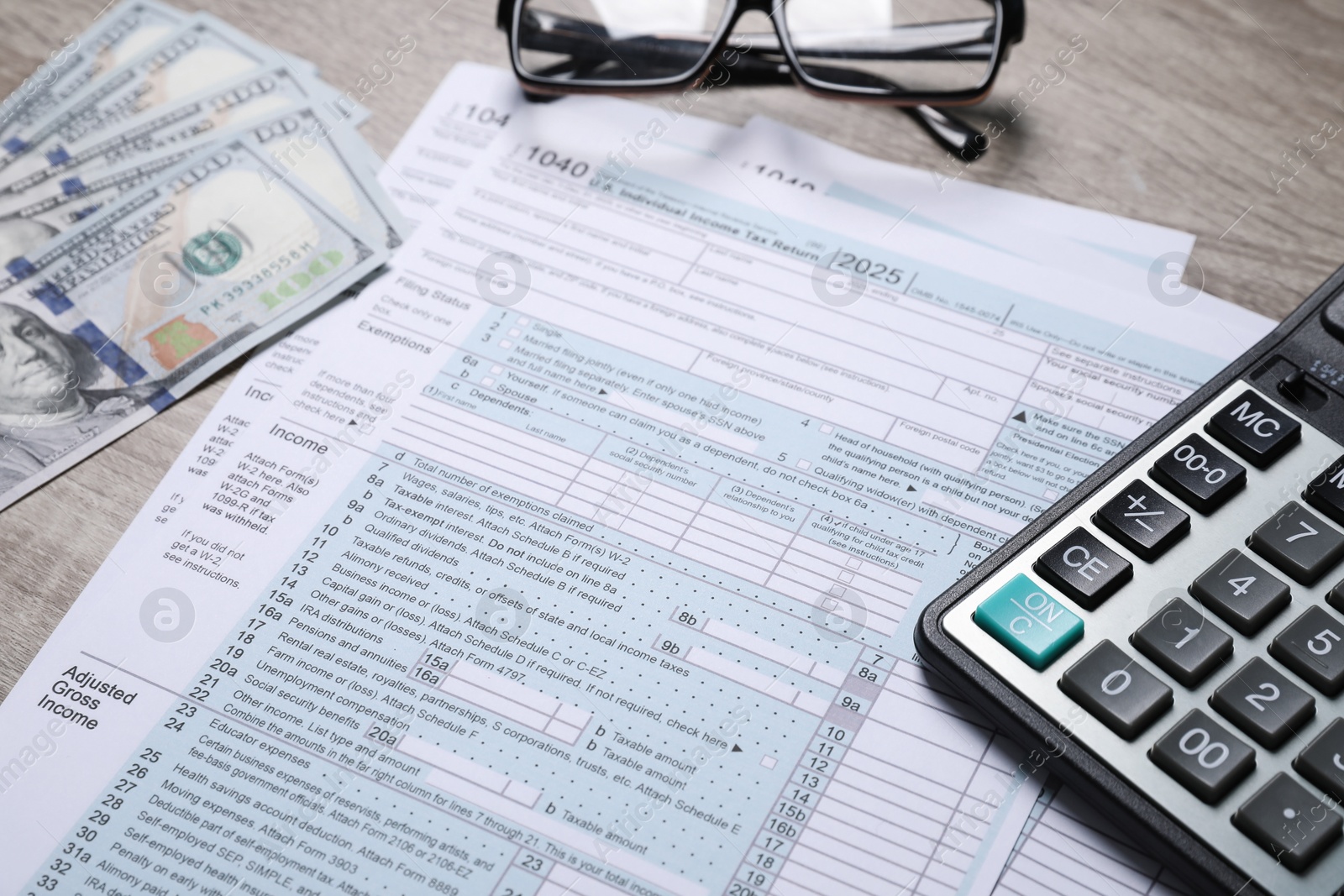 Photo of Payroll. Tax return forms, dollar banknotes and calculator on wooden table