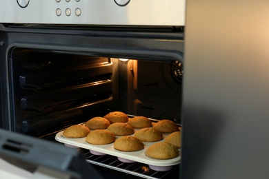 Photo of Baking pan with cupcakes in modern oven