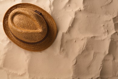 Photo of Stylish straw hat on sand, top view. Space for text
