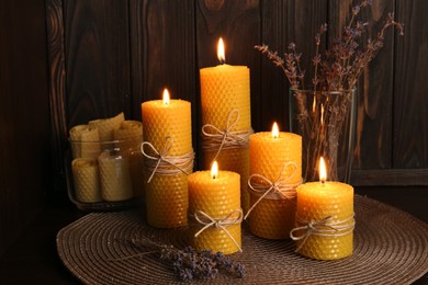 Photo of Beautiful burning beeswax candles and dried lavender flowers on table