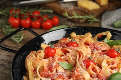 Tasty pasta with tomatoes, cheese and basil on wooden table, closeup