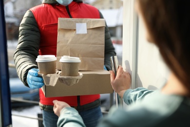 Photo of Courier giving to woman her order at doorway, closeup. Delivery service during Covid-19 quarantine