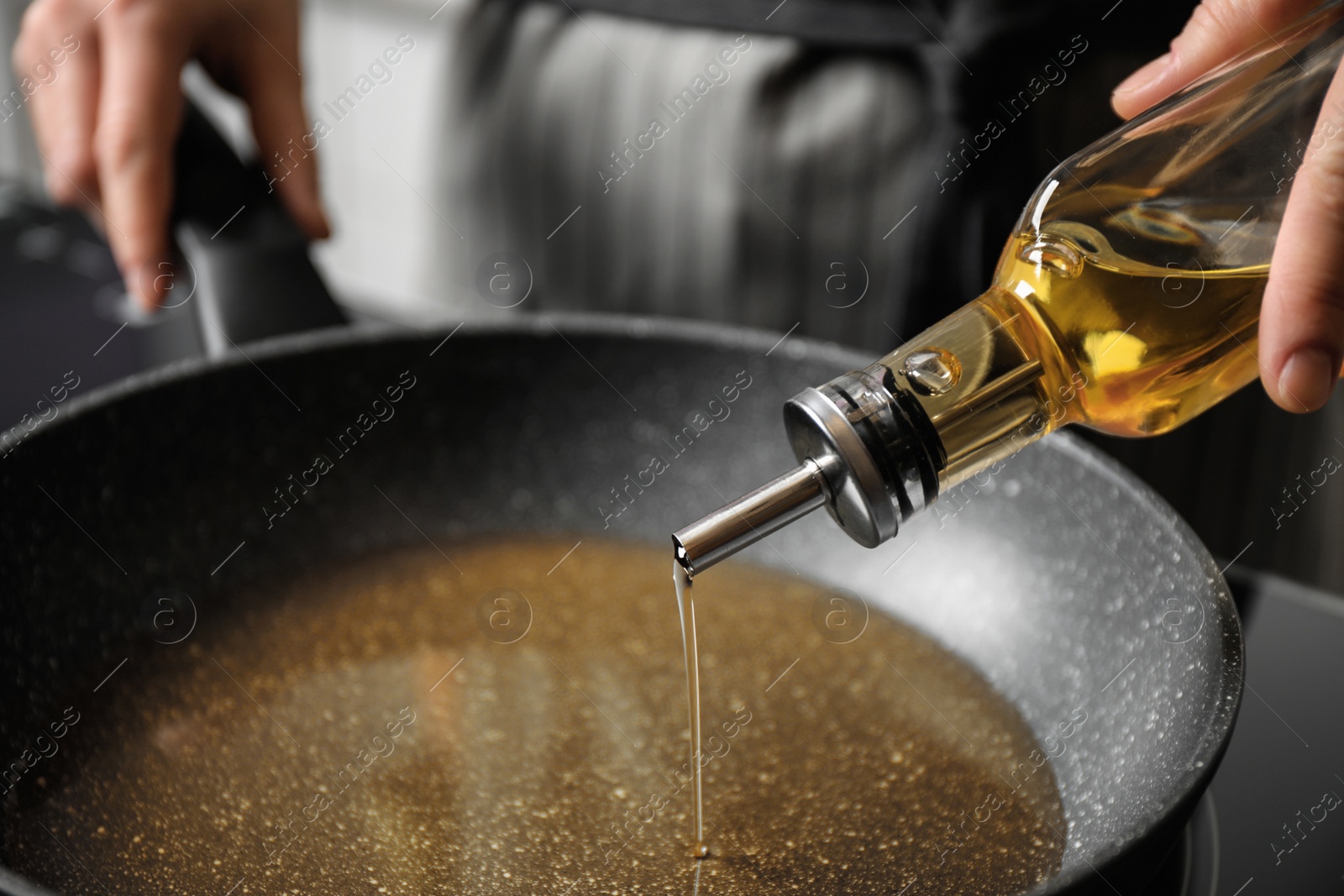 Photo of Woman pouring cooking oil from bottle into frying pan, closeup