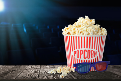 Image of Popcorn, 3D glasses in cinema on table and empty cinema hall, space for text 