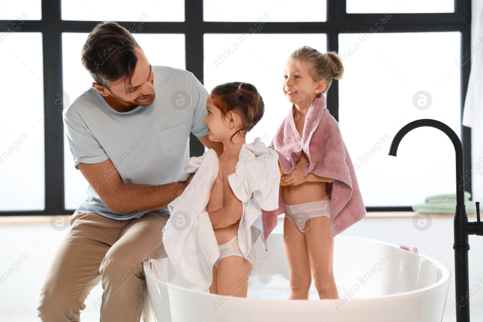 Photo of Young father with little daughters in bathroom