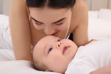 Photo of Young mother with her little baby on bed, closeup