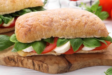 Photo of Delicious Caprese sandwiches with mozzarella, tomatoes and basil on white wooden table, closeup
