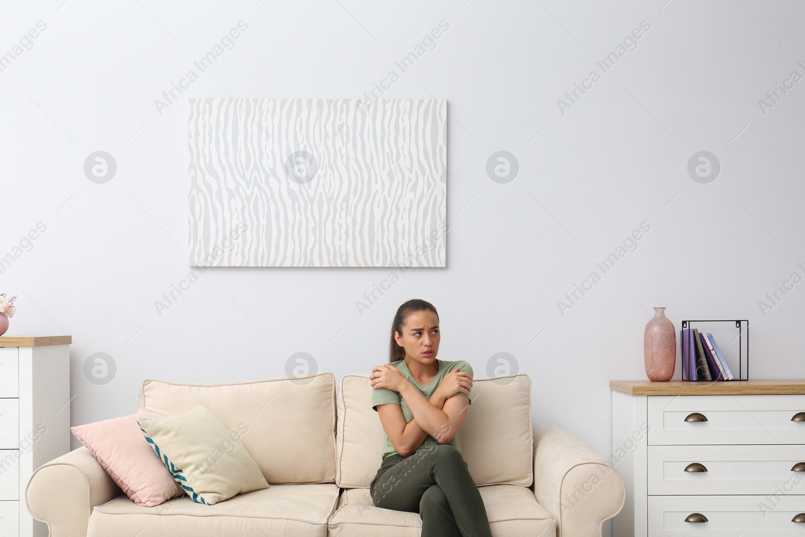 Photo of Young woman freezing under air conditioner at home