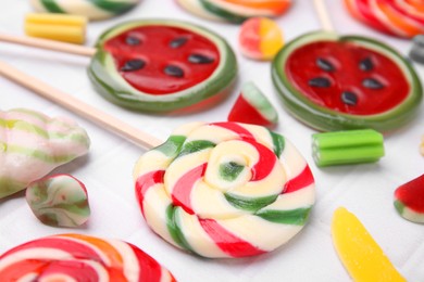 Photo of Many tasty colorful lollipops and jelly candies on white tiled table, closeup