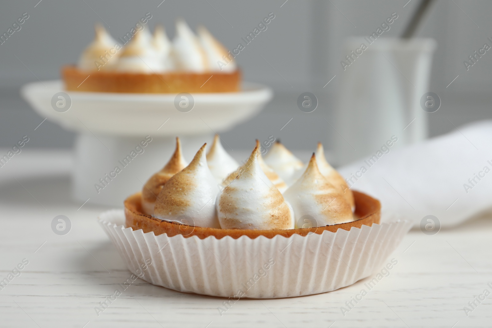 Photo of Tartlet with meringue on white table, closeup. Delicious dessert