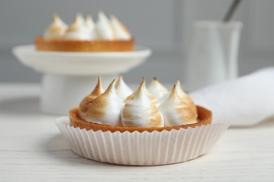 Tartlet with meringue on white table, closeup. Delicious dessert