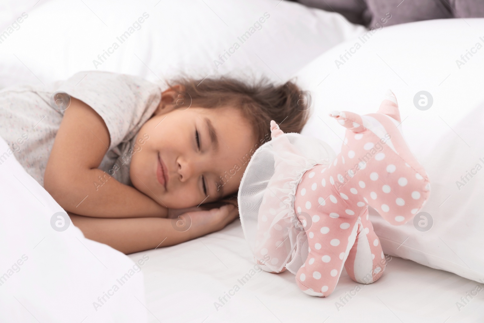 Photo of Cute little girl with toy sleeping in bed