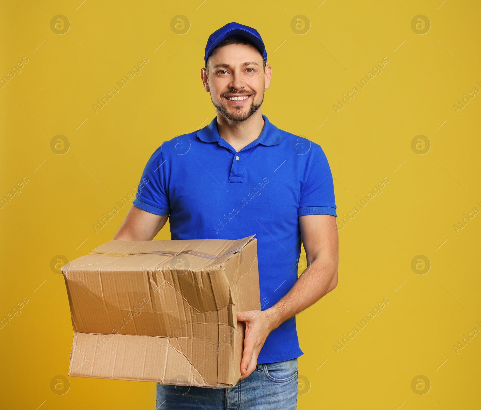 Photo of Courier with damaged cardboard box on yellow background. Poor quality delivery service