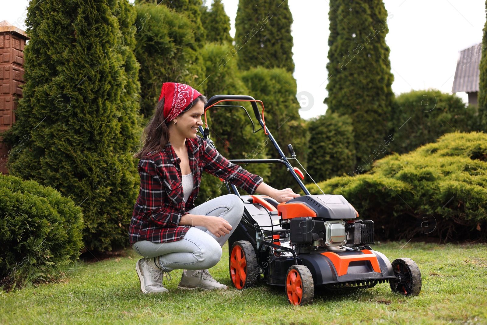 Photo of Smiling woman with modern lawn mower in garden
