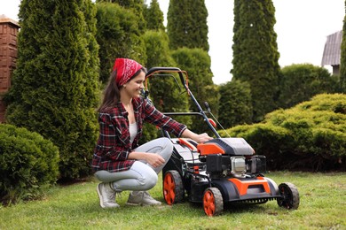 Smiling woman with modern lawn mower in garden