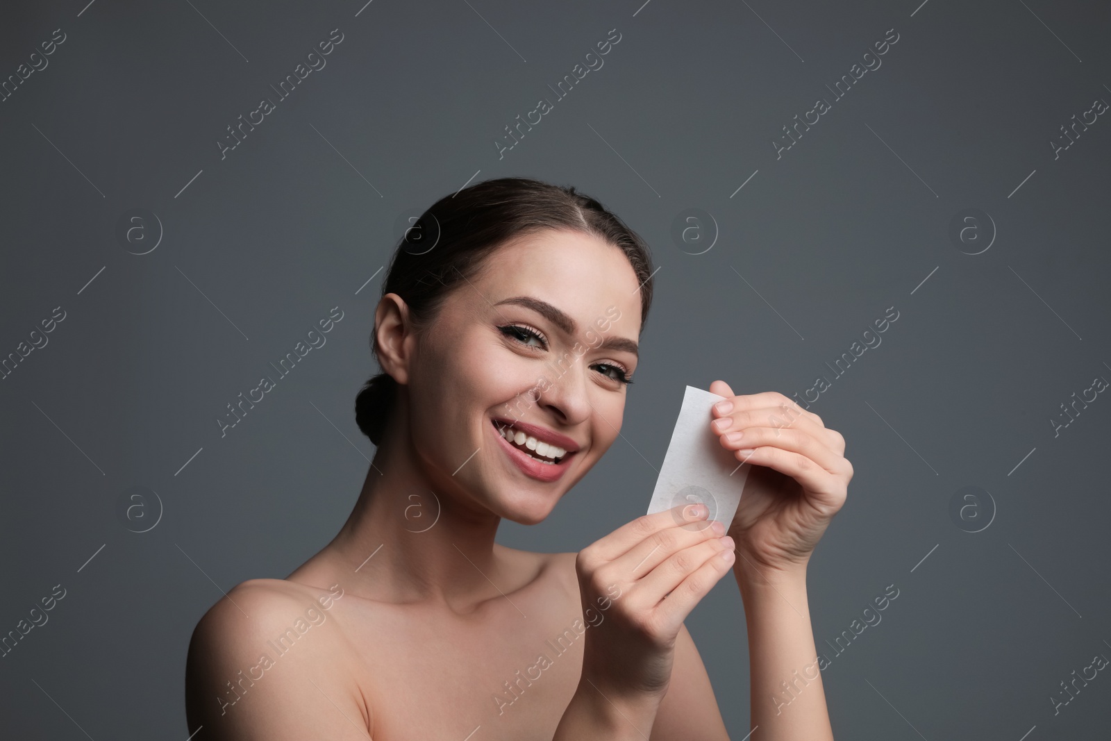 Photo of Beautiful woman with mattifying wipe on grey background