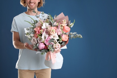 Man holding beautiful flower bouquet on blue background, closeup. Space for text