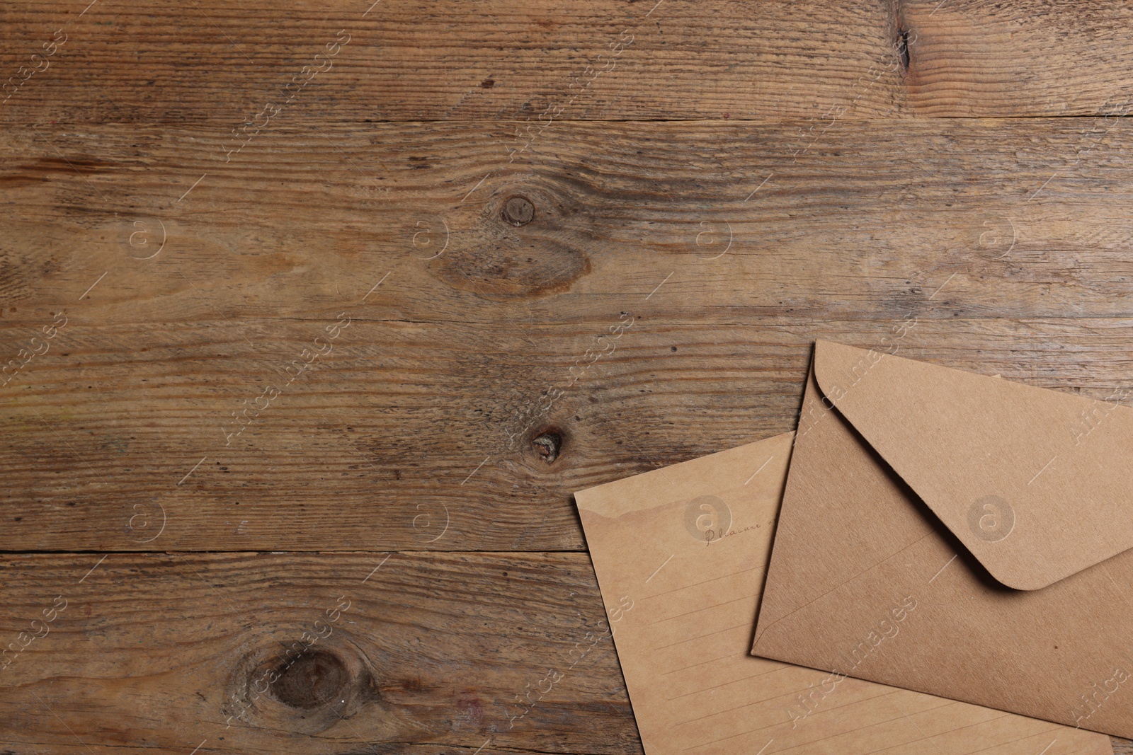 Photo of Envelope and sheet of parchment paper on wooden table, flat lay. Space for text