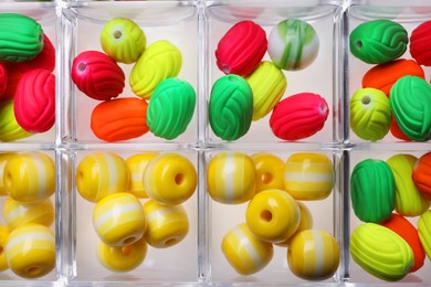 Photo of Plastic organizer with different beads as background, top view