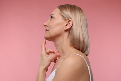 Photo of Beautiful woman touching her neck on pink background