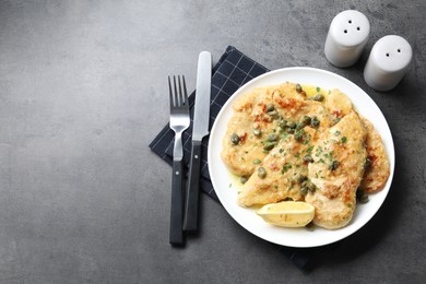 Delicious chicken piccata with herbs served on grey table, flat lay. Space for text