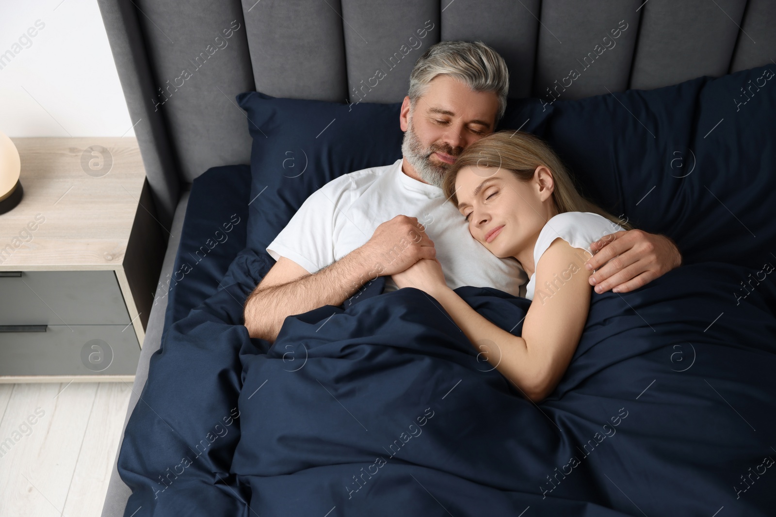 Photo of Lovely mature couple sleeping together in bed at home, above view