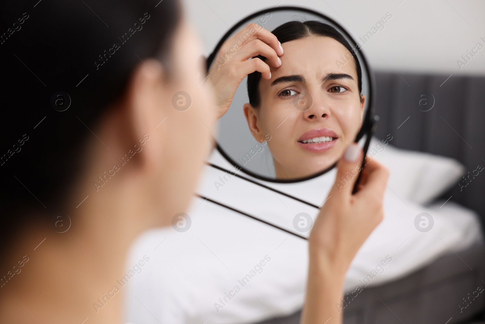 Photo of Woman with dry skin looking at mirror indoors