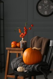 Photo of Beautiful autumn composition with pumpkins and blanket on chair indoors