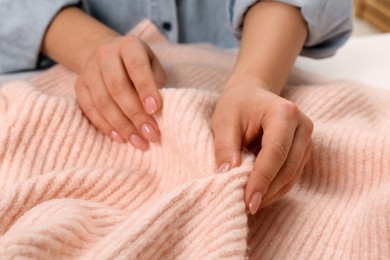 Photo of Woman touching soft pink knitted fabric, closeup