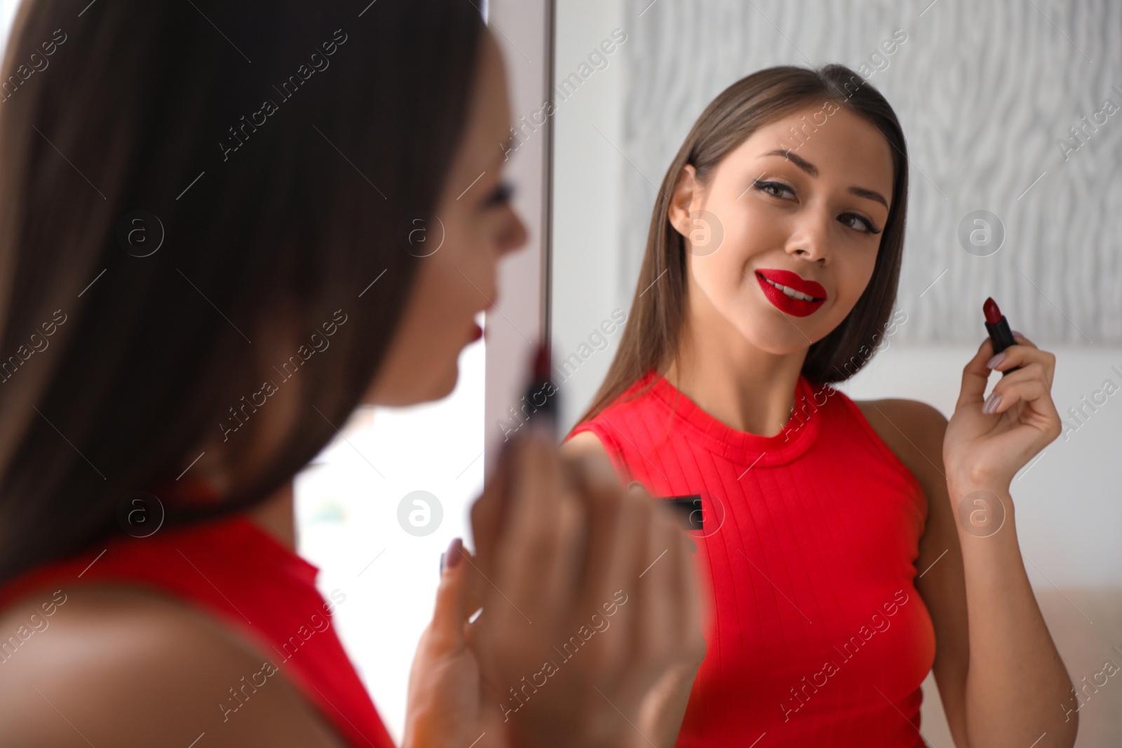 Photo of Beautiful woman with red lipstick near mirror