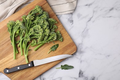 Photo of Fresh raw broccolini and knife on white marble table, flat lay with space for text. Healthy food