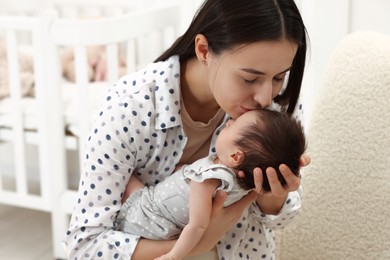 Photo of Mother kissing her sleeping newborn baby indoors