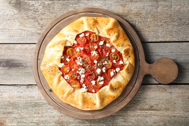 Photo of Tasty galette with tomato, thyme and cheese (Caprese galette) on wooden table, top view