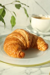 Delicious fresh croissant on white marble table, closeup