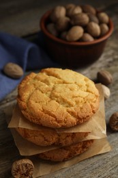 Tasty cookies and nutmeg seeds on wooden table, closeup