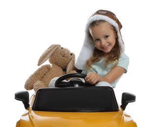 Cute little girl with toy bunny driving children's car on white background