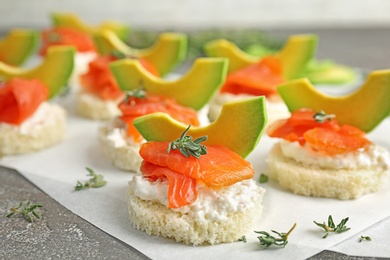 Photo of Tasty sandwiches with fresh sliced salmon fillet and avocado on table, closeup