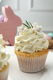 Photo of Tasty Easter cupcake with vanilla cream on table, closeup