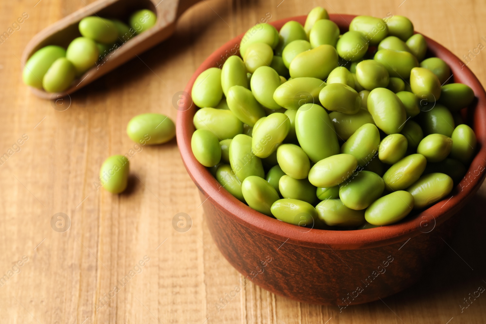 Photo of Bowl of delicious edamame beans on wooden table