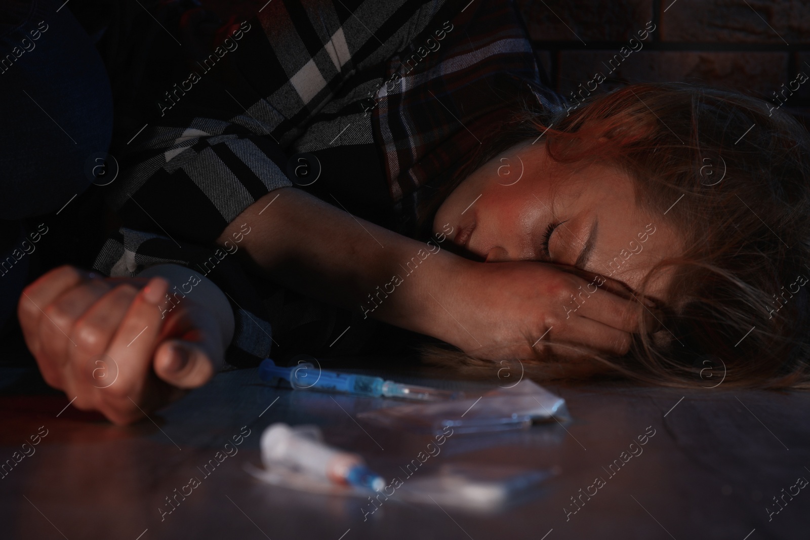 Photo of Addicted woman near different drugs on floor