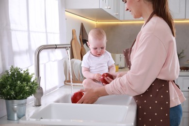 Mother and her cute little baby spending time together in kitchen