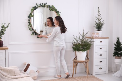 Photo of Woman decorating mirror with eucalyptus branches at home